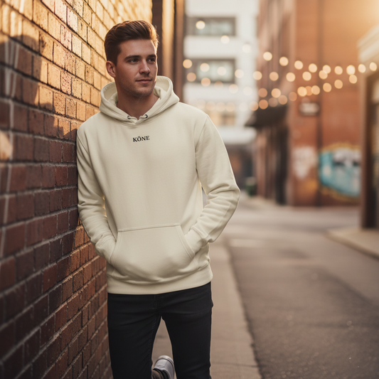 Modelo con sudadera KÖNE color crema paseando en entorno urbano al atardecer