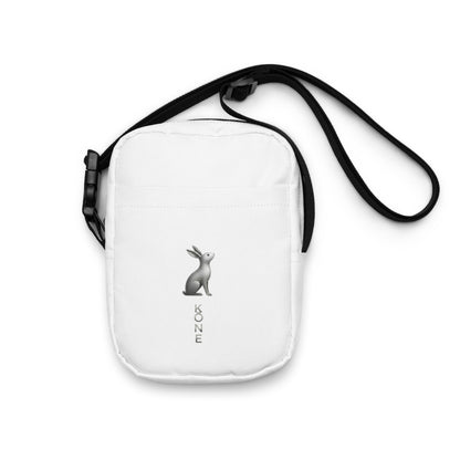 Bandolera KÖNE blanca con logo gris metalizado, diseño vertical minimalista