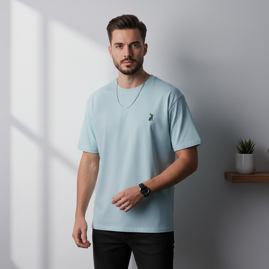 Hombre con camiseta KÖNE celeste, logo verde bordado, estilo casual y corte estructurado.
