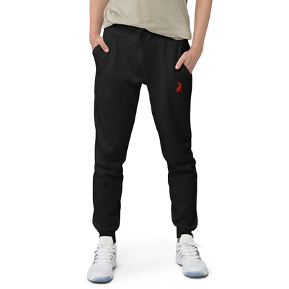 Hombre con pantalón de chándal negro KÖNE y logo del conejo rojo en la pierna izquierda, fondo blanco.