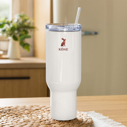 Tumbler KÖNE blanco de acero inoxidable sobre una mesa de madera, con tapa transparente y logo rojo